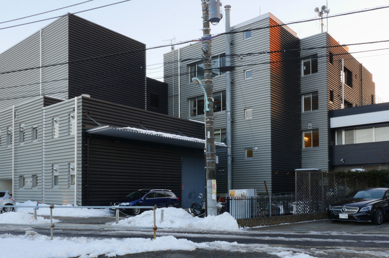 バックヤード側外壁|片岡直樹の建もの探訪|清瀬けやきホール 既存建物部分の鉄筋コンクリート外壁部分と思われるところが2種類の金属折半貼りで覆われています。装飾的です。