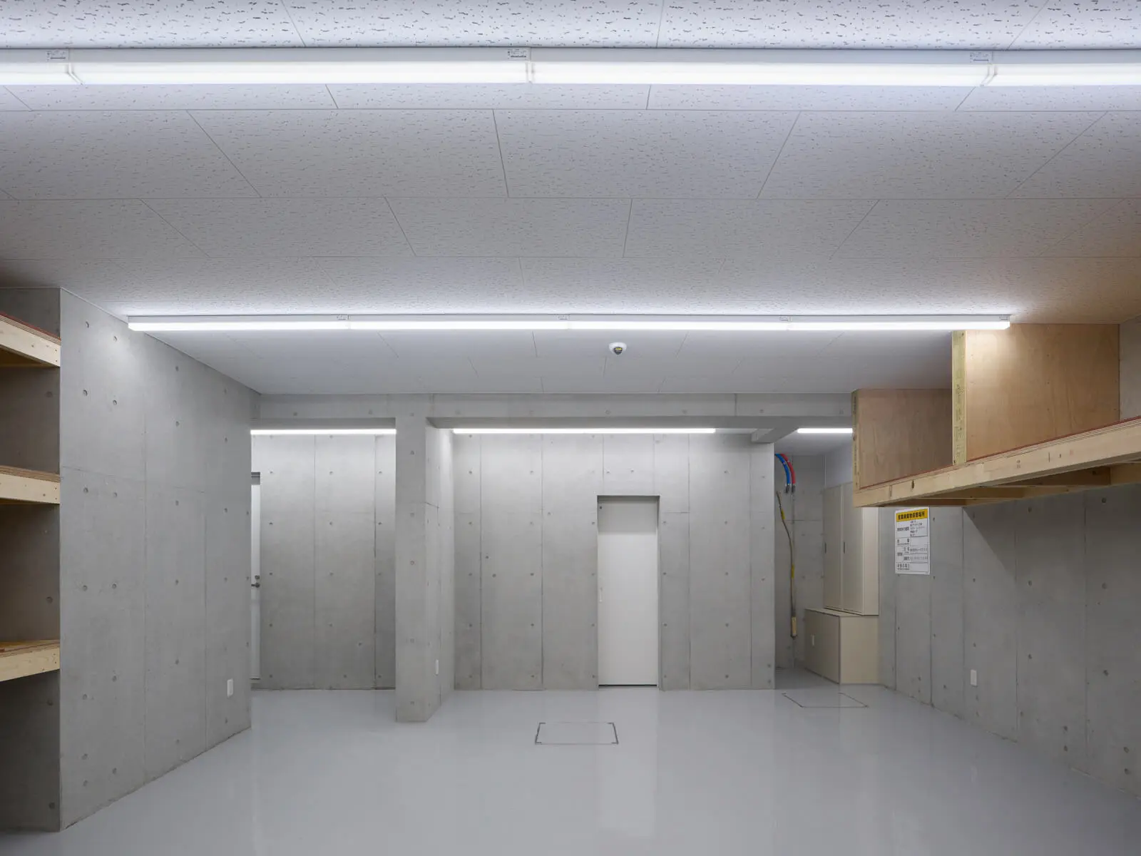 オフィスビル1階倉庫の正面カット。コンクリート壁式構造の強固な躯体を活かし、仕上げコストを抑えた機能的な空間設計。