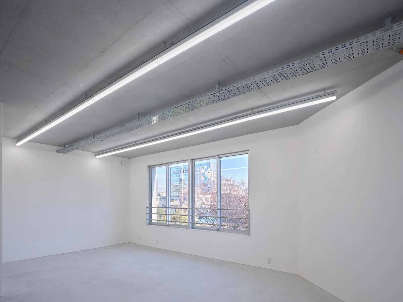 公園の緑を望む自社ビル3階オフィス。天井配線とコンクリート現し仕上げを採用し、コスト削減と開放感を両立。