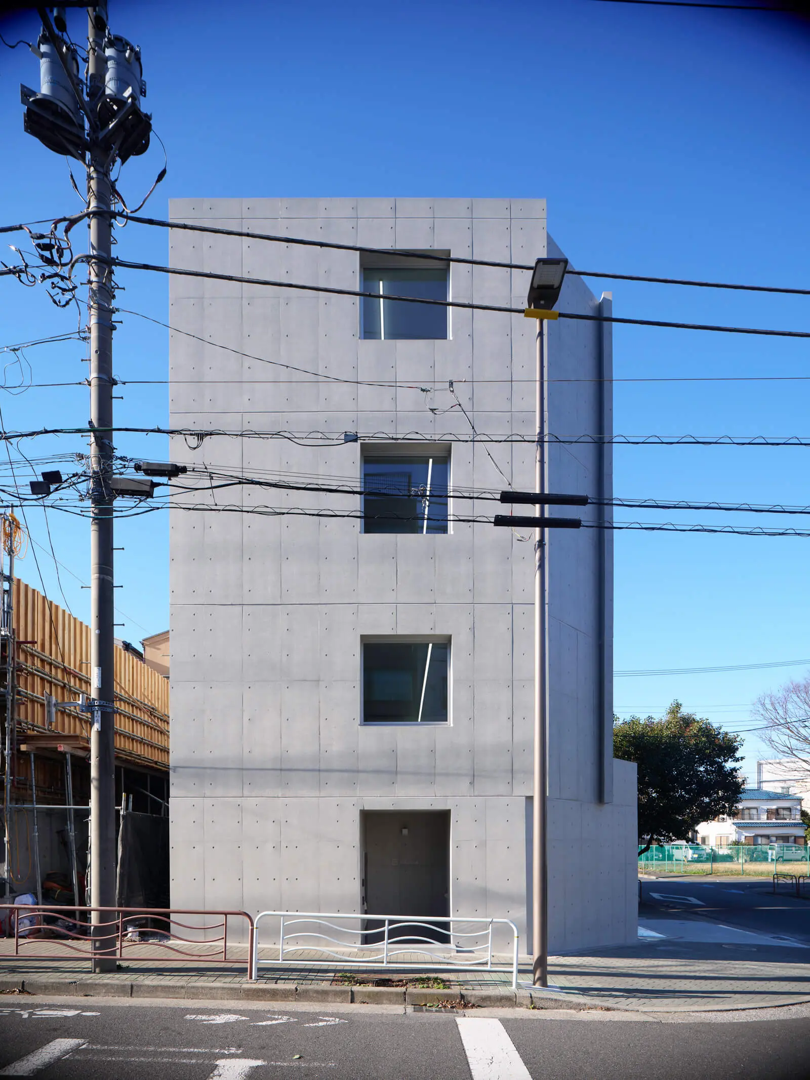 建築費を削減したRC造4階建てオフィスビルの南側外観。窓とエントランスの開口幅を揃え型枠転用を容易に。