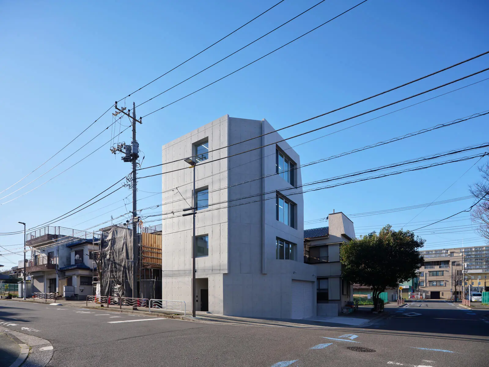 鉄筋コンクリート壁式構造を採用した4階建て自社ビルの南東角ファサード。厚い壁に穿たれた開口部が特徴的。