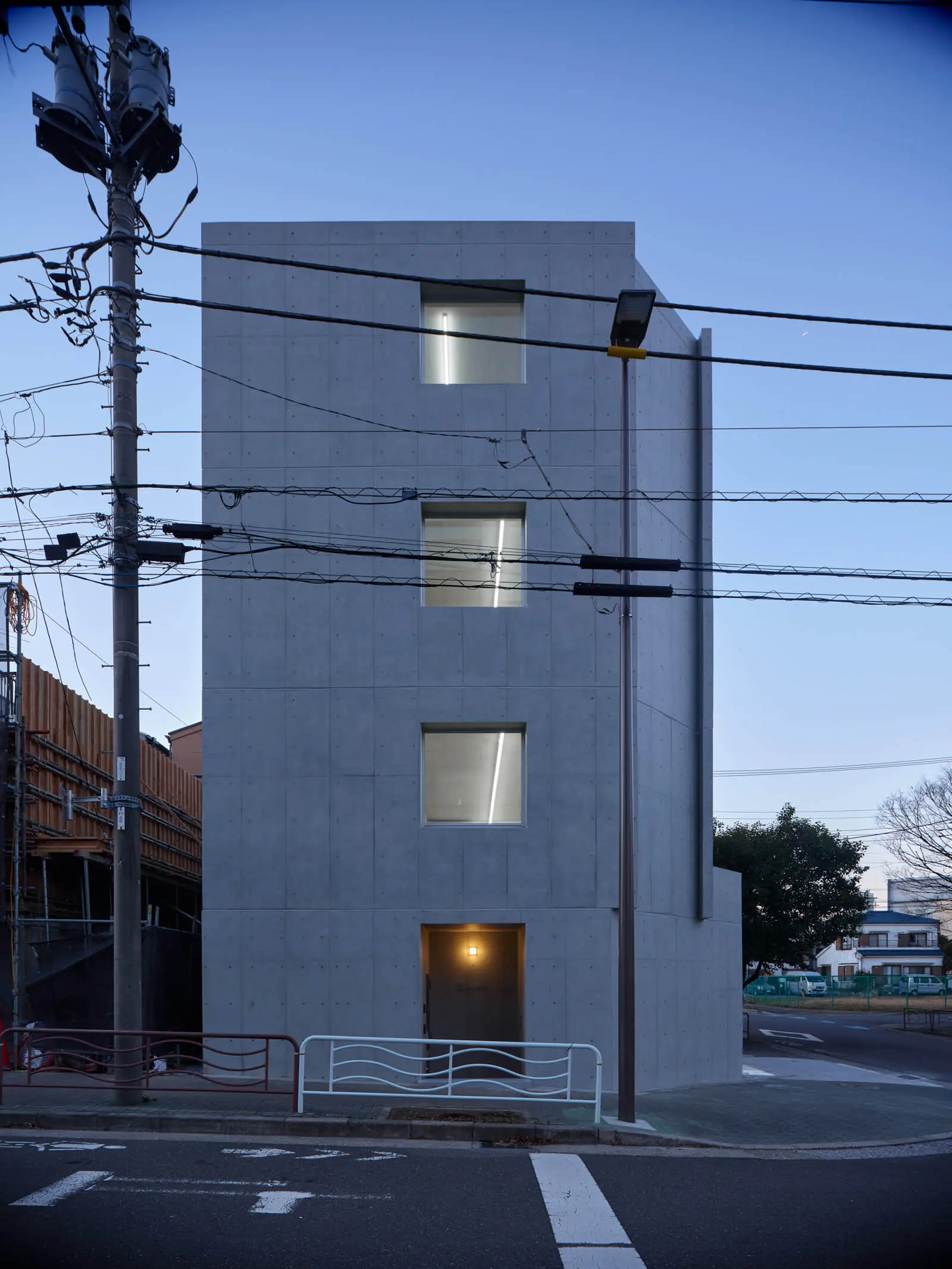 江東区潮見の自社ビル・オフィス建築の南側外観（夕景）。コンクリートの躯体から漏れる室内の温かな灯り。