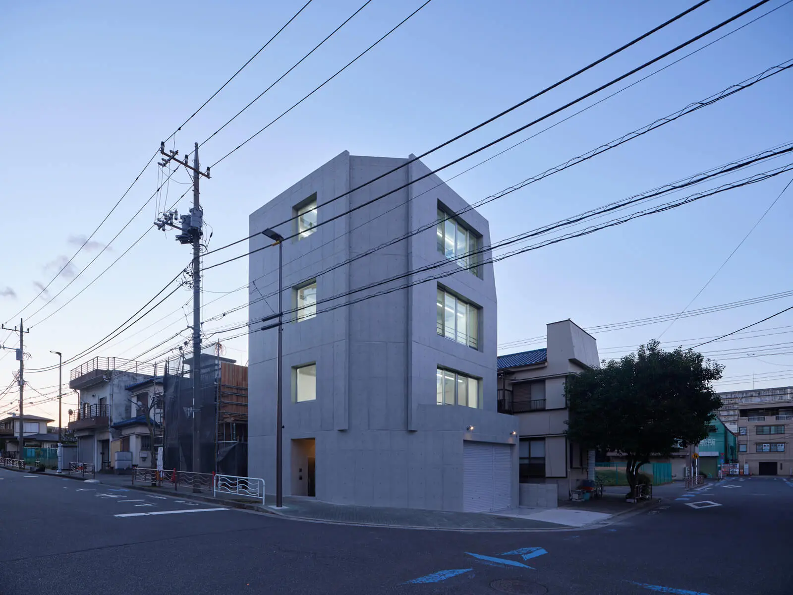 RC造4階建てオフィスビルの東南角外観（夕景）。大きな窓から溢れる光が街を照らす、魅力的な自社ビル事例。