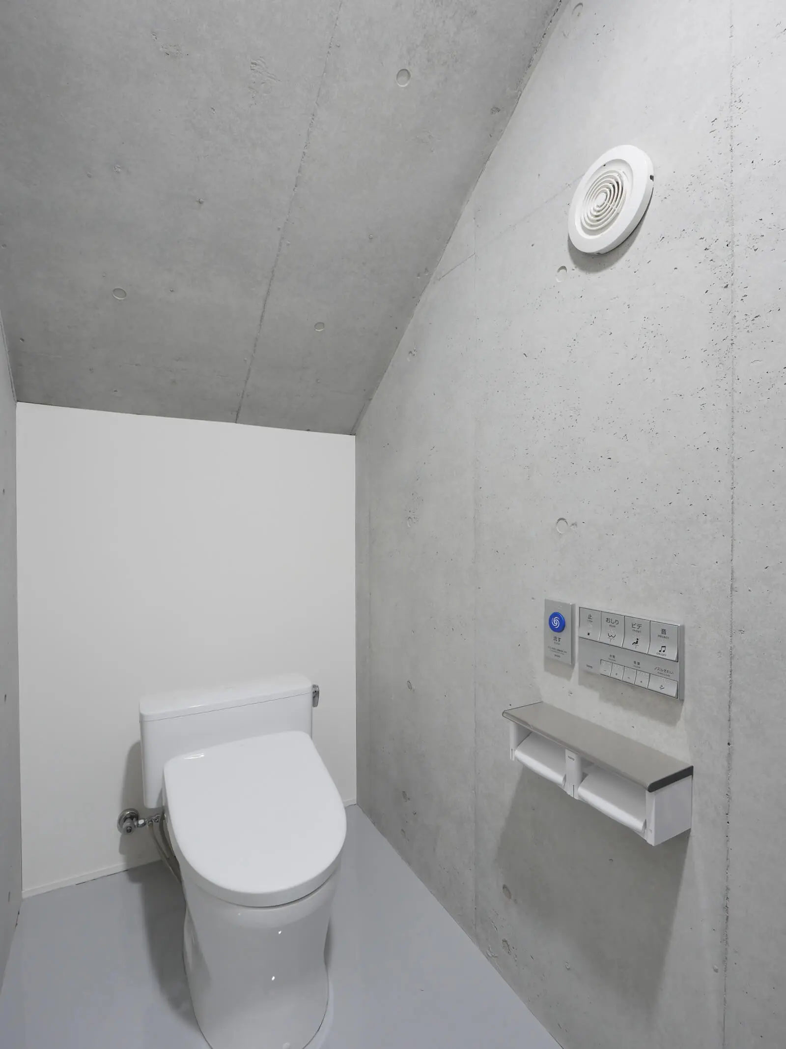 階段下のデッドスペースを活用し建築コストを抑えた、江東区潮見の自社ビル1階トイレ（RC打放し）。