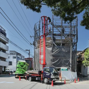 東京都江東区で建設中の鉄筋コンクリート造・コンクリート打放し仕上げ4階建てオフィスビル。東側外観。コンクリート圧送ポンプ車と生コンクリートミキサー車によるコンクリート打設の様子。