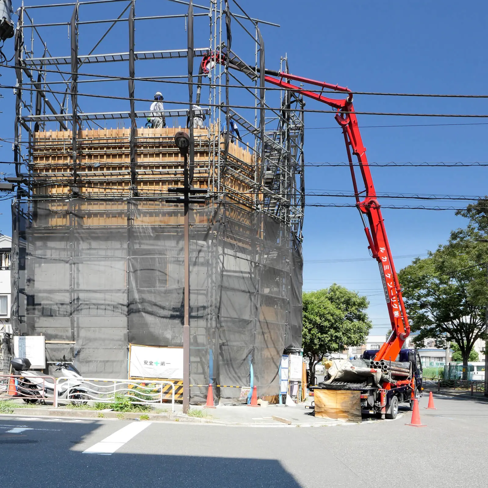 東京都江東区で建設中の鉄筋コンクリート造・コンクリート打放し仕上げ4階建てオフィスビル。南側外観。東側道路にコンクリート圧送ポンプ車を配置し、コンクリート打設を行っている様子。