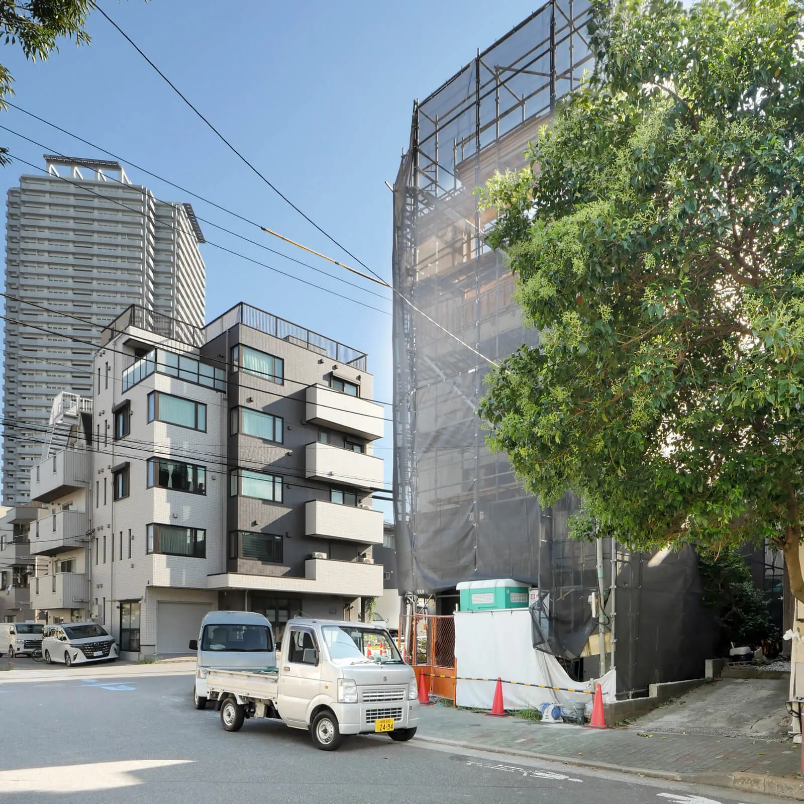 江東区潮見で建設中のRC造4階建てコンクリート打ち放しオフィスビル。4階型枠工事中、街路樹のある歩道から見た北東側外観と躯体工事の進捗状況。