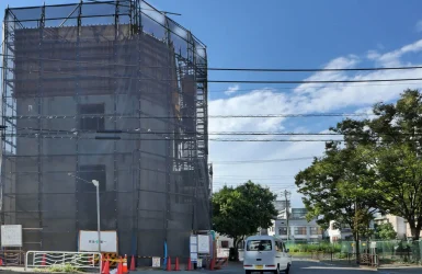 江東区潮見で建設中のRC造4階建てコンクリート打ち放しオフィスビル。4階型枠工事中、公園の樹木より高く立ち上がった南側外観と躯体工事の進捗状況。